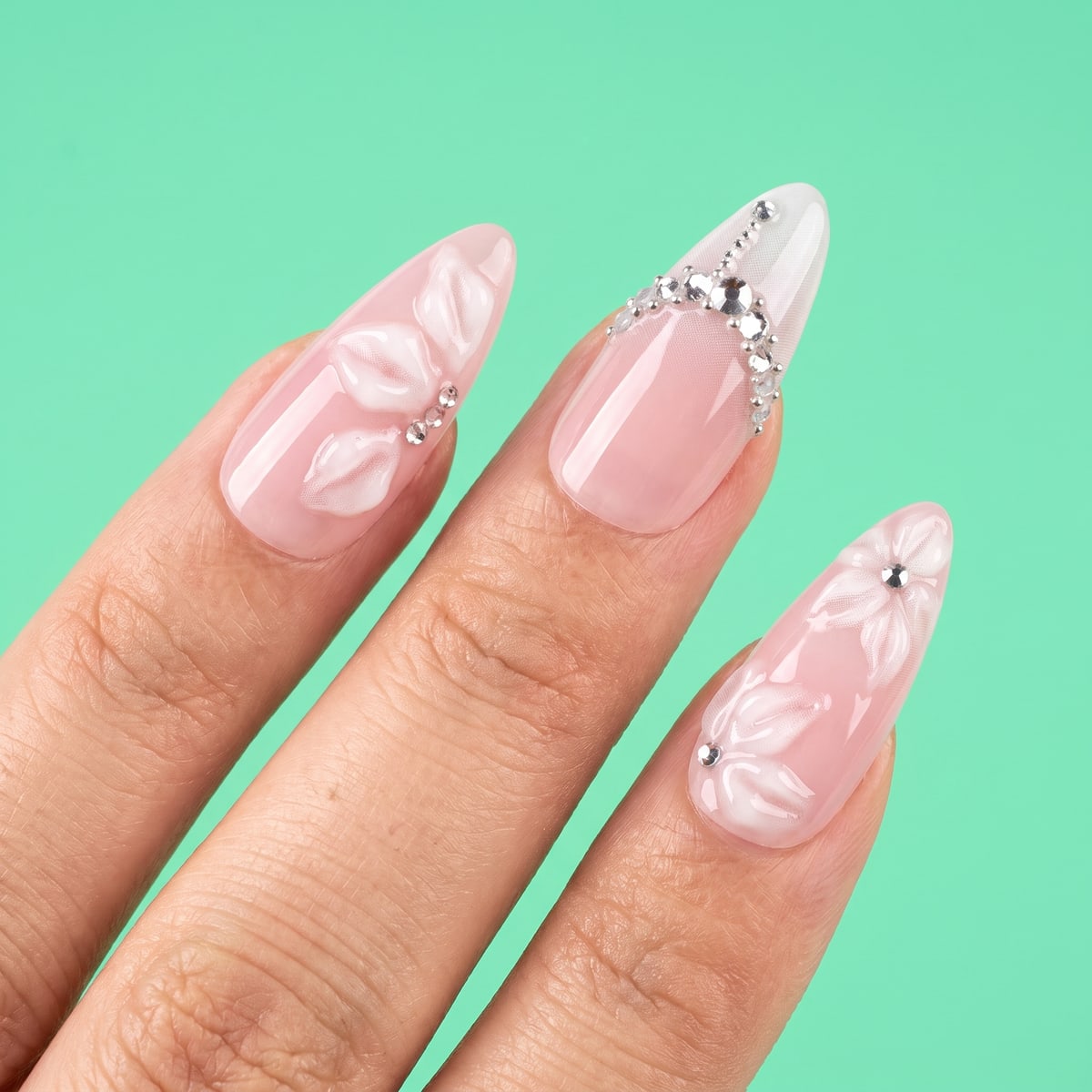Macro texture tile: blush almond nails with 3D sculpted flowers and rhinestones on mint green