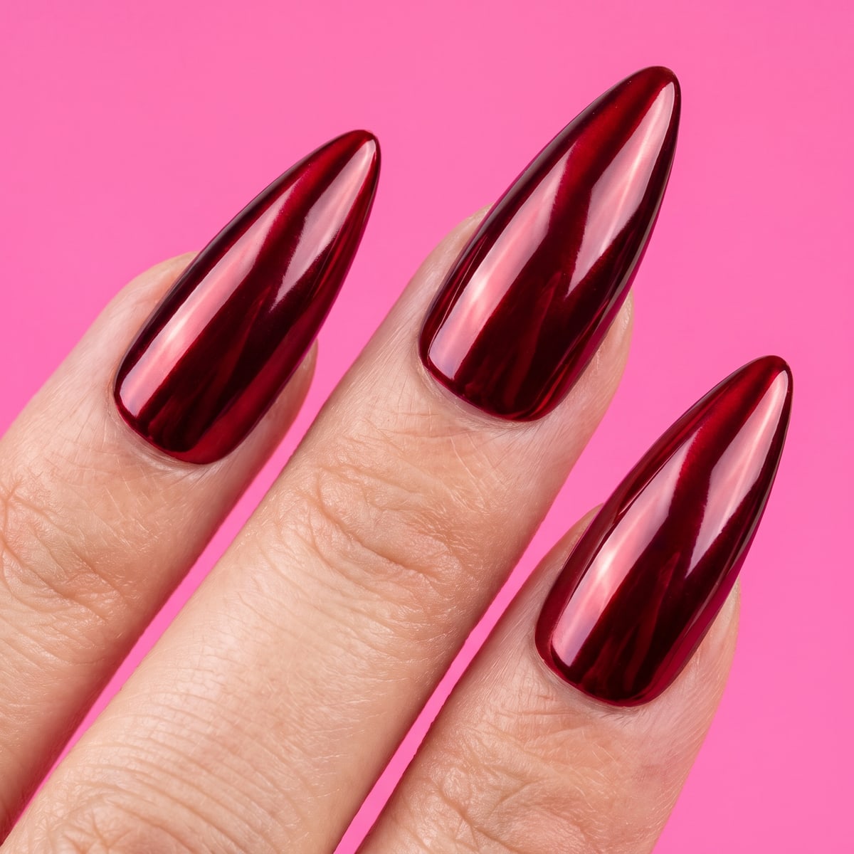 Macro texture tile: deep red mirror-chrome stiletto nails on bubblegum hot-pink