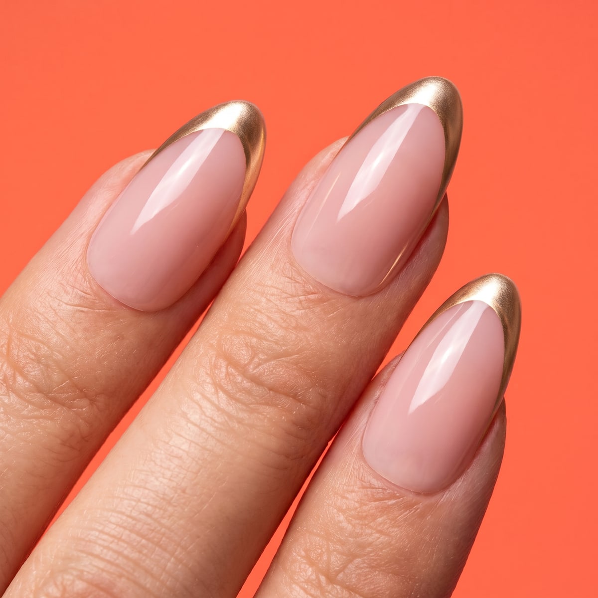 Macro texture tile: nude pink almond nails with fine gold french tips on coral orange