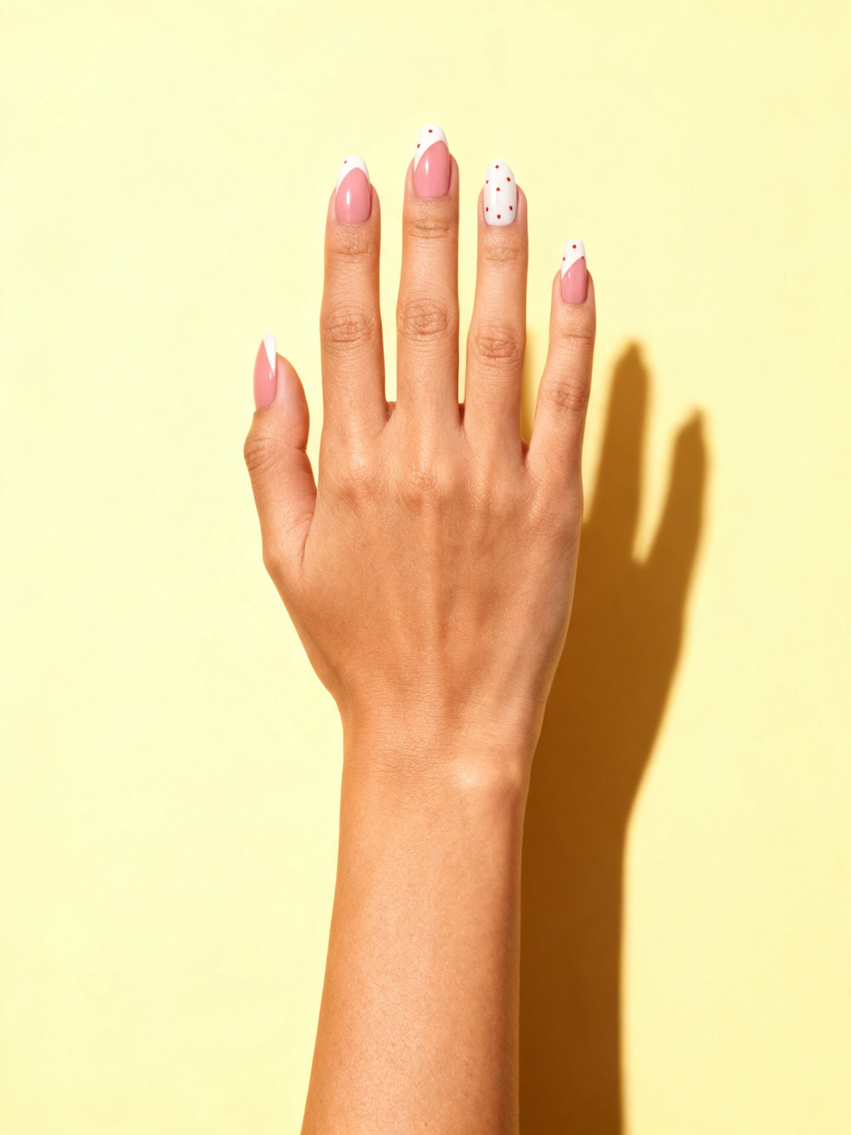 Red Polka Dot Almond Press-On Nails on a hand